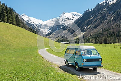 Vintage VW Bully camping car driving on mountain valley road Stock Photo