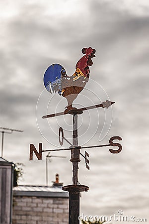 vintage weathercock in the shape of a colorful rooster on a French roof Stock Photo