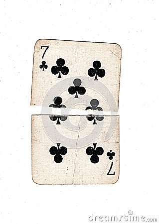 A vintage seven of clubs playing card torn in half. Stock Photo