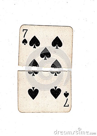 A vintage seven of spades playing card torn in half. Stock Photo