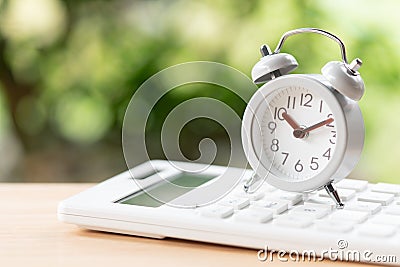 Vintage White Alarm Clock placed on a white calculator using as Stock Photo