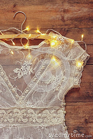 Vintage white crochet lace top on hanger with garland lights on wooden background Stock Photo