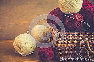 Vintage wicker chest bolls clews of red white wool yarn, needles on wood table, knitting, crafts, hobby concept Stock Photo