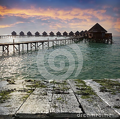 Vintage wooden board with sea, beach and lodges over water background Stock Photo