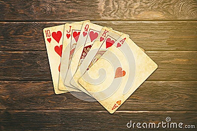 Vintage worn out hearts royal flush poker cards wooden table top Stock Photo