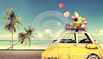 Vintage yellow car with heart colorful balloon on beach Stock Photo