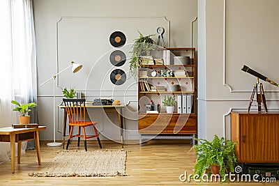 Vinyl records decorations on a gray wall with molding and wooden furniture in a retro home office interior for a writer. Real phot Stock Photo