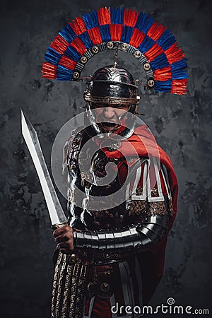 Violent legionnaire wielding gladius screaming against dark background Stock Photo