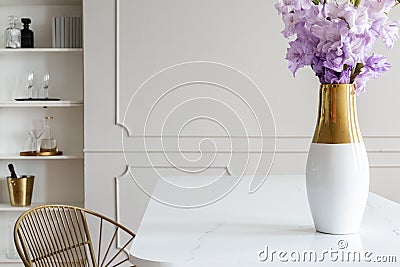 Violet flowers on white table in simple dining room interior with wall with molding. Real photo Stock Photo