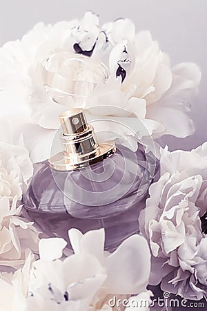 Violet fragrance bottle as luxury perfume product on background of peony flowers, parfum ad and beauty branding Stock Photo