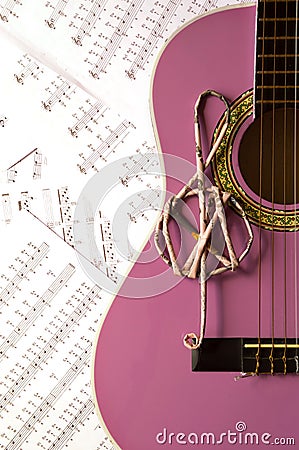 Violet guitar for children with treble clef on music sheets back Stock Photo