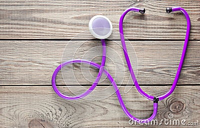 Violet stethoscope on a wooden table. Medical cardiology equipment. Stock Photo