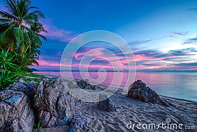 Violet sunset over the sea and rocky beach Stock Photo