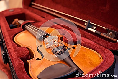 Violin and bow in dark red case. Close up view of a violin strings and bridge Stock Photo