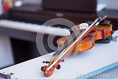 Violin and bow on table with blured brown piano in background Stock Photo