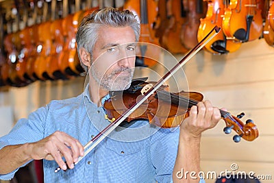 Violin maker while testing violins in laboratory Stock Photo