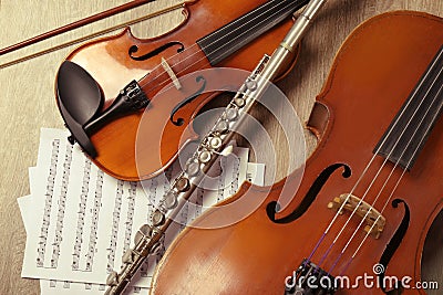 Violin, violoncello, flute and note sheets on wood, flat lay. Musical instruments Stock Photo