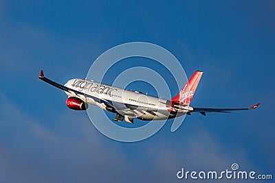 A Virgin Atlantic Airbus A330-300 flies against a bright blue sky Editorial Stock Photo