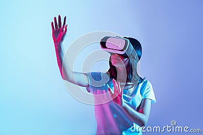 Virtual game of new generation. Girl in glasses examining something and raises hands Stock Photo