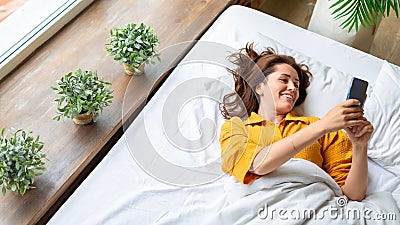 Virtual love - woman lies in bed with cell phone. Online call to virtual boyfriend. Stock Photo