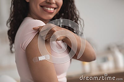 Happy young pretty african american female showing arm with band-aid after getting vaccination Stock Photo