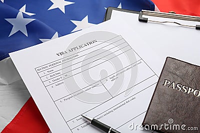 Visa application form, clipboard and passport on American flag, closeup Stock Photo