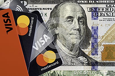 VISA and Master Card bank cards on a 100 US dollars banknote. VISA American multinational financial services corporation. Editorial Stock Photo