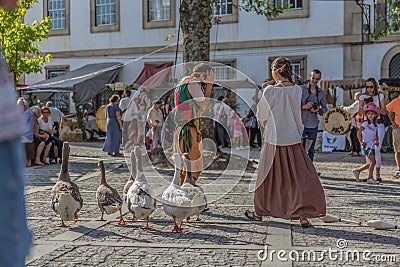 Spectacle view with street theater, medieval fair, actors dressed in typical costumes, walking geese and public watching Editorial Stock Photo