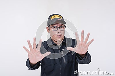 A visibly afraid security guard tells someone to stop. A fearful asian guy gesturing with open palms, begging to spare his life. Stock Photo
