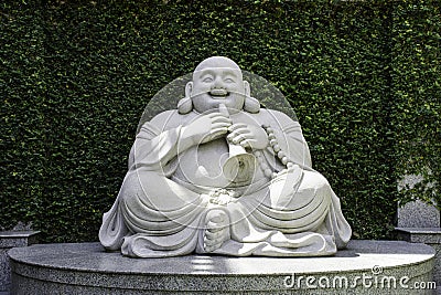 The marble laughing Buddha statues locate on green garden outdoor Editorial Stock Photo