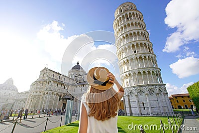 Visiting the Leaning Tower of Pisa, famous landmark of Italy. Young traveler woman in Piazza del Duomo square in Pisa, Tuscany, Stock Photo