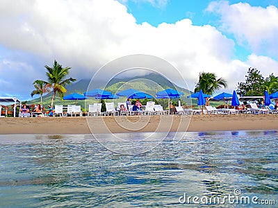 Visitors On Lounge Chairs Under Umbrellas at Pinney's Beach, Nevis Editorial Stock Photo