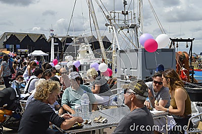 Visitors sit by the harbour to sample oysters at the Whitstable Oyster Festival Editorial Stock Photo