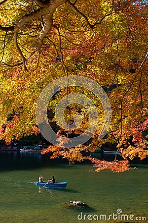 Visitors take in the colors of autumn along the Hozu-gawa River in Kyoto while riding a wooden boat Stock Photo
