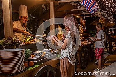 Visitors taking food during the international cuisine dinner outdoors setup at the tropical island restaurant Editorial Stock Photo