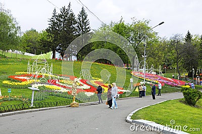 Visitors walking at the park and looking at bright tulips planted on a lawn Editorial Stock Photo