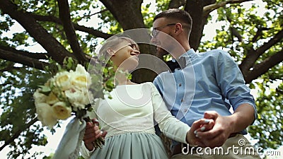 Vista dal basso Giovane bello bacio delle persone appena sposate contro un fondo dell'albero verde nel parco video d archivio Vista dal basso Giovane bello bacio delle persone appena sposate contro un fondo dell'albero verde nel parco video d archivio