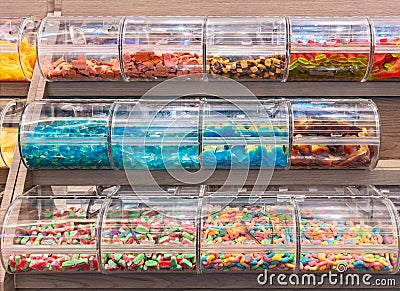 Colorful gelatin-based chewable confectionery gummi candies stored in clear plastic display boxes. Stock Photo