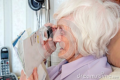 Visually impaired elderly woman with magnifying loupe Stock Photo