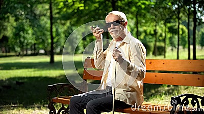 Visually impaired old man using voice control app in smartphone, innovations Stock Photo