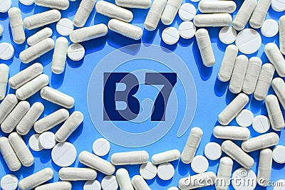 Vitamin B7 text in white capsules frame on blue background. Pill with Biotin Stock Photo