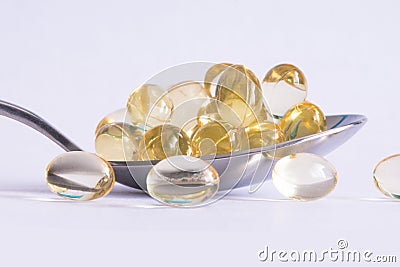 Vitamin D supplement pills close up or macro view in a spoon suggesting choosing a natural alternative to lower the risk of illnes Stock Photo