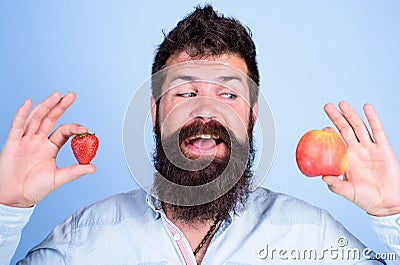 Vitamin fruit nutrition concept. Healthcare dieting vitamin. Man bearded smiling holds apple and strawberry in hands Stock Photo