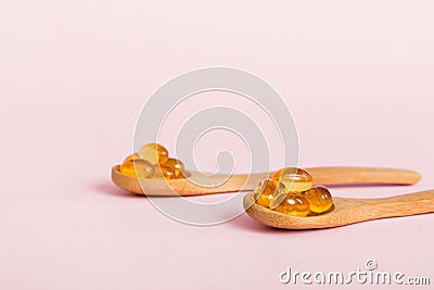 Vitamin omega capsules in a spoon on a colored background. Pills served as a healthy meal. Red soft gel vitamin Stock Photo