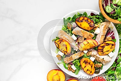 Vitamin salad with grilled chicken and peach, feta cheese and walnuts in a plate. healthy food. top view Stock Photo