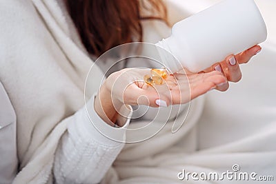 Vitamins and food supplements concept. Female hand pouring yellow pills out of bottle into palm. Woman spilling out Stock Photo