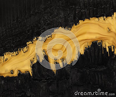 Vivid contrast black and gold in abstract background of metallic gold paint swirling over charred black ashes Stock Photo