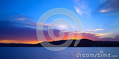 Vivid crimson and blue Seascape sunset with water reflections. Stock Photo