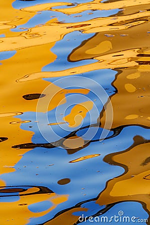 Vivid red, orange, blue and golden tones reflect in water on sunset in the river Spree in Berlin, can be used as colorful abstract Stock Photo