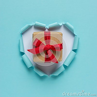 Vivid torn paper heart with gift box on bright background. Stock Photo